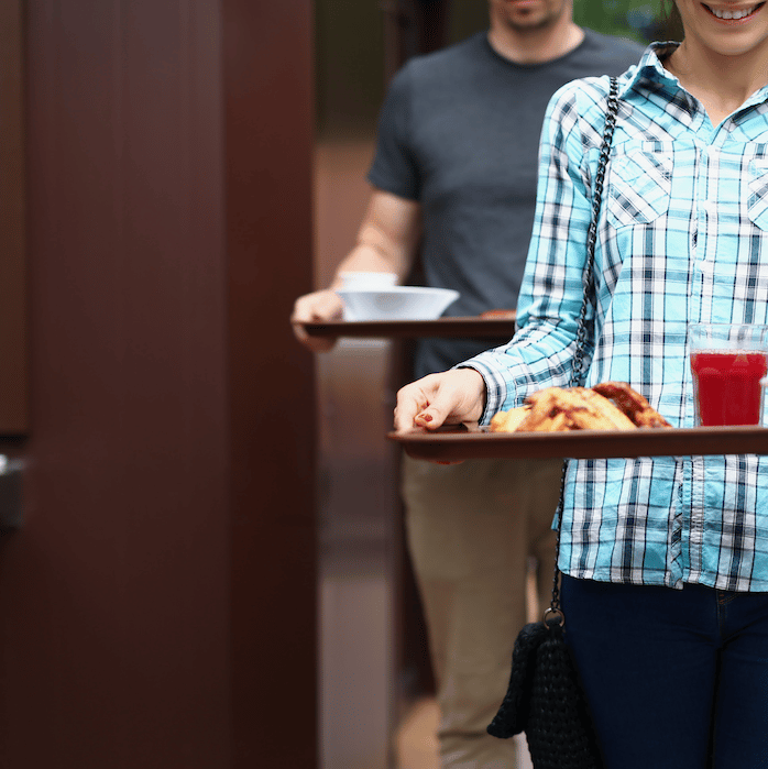 Due persone che camminano trasportando un vassoio con del cibo